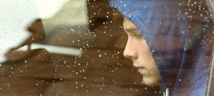 Sad boy looking out a rainy car window