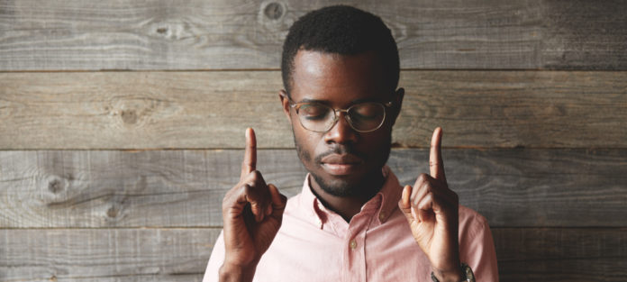 A man closing his eyes, pointing upwards