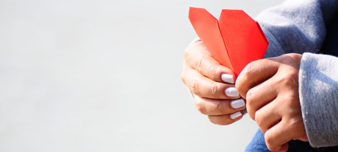 Hands holding paper heart