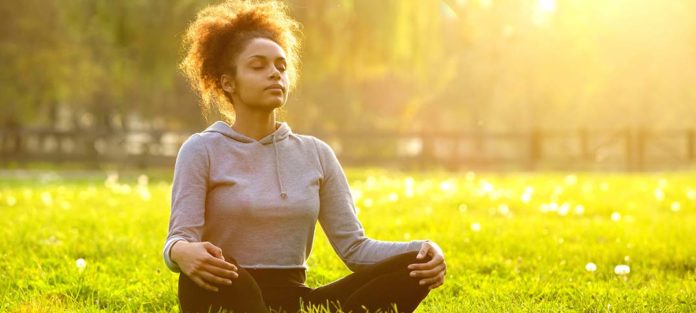 young african american woman meditating in nature with eyes closed
