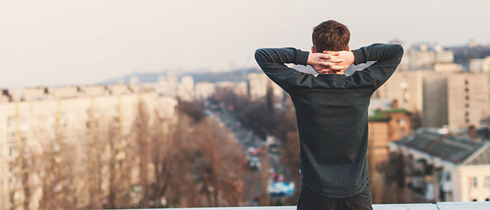 Guy standing on rooftop alone looking at the city
