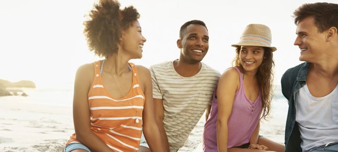 Happy students sitting on a beach