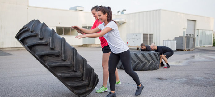 Two girls flipping large truck tire