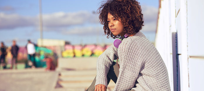 Girl sitting outside, looking out into the distance