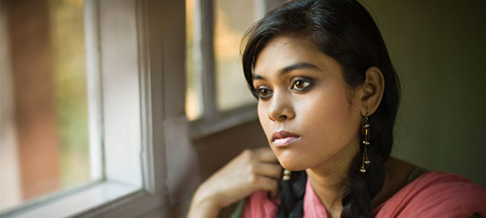 Young woman looking out the window with a serious expression