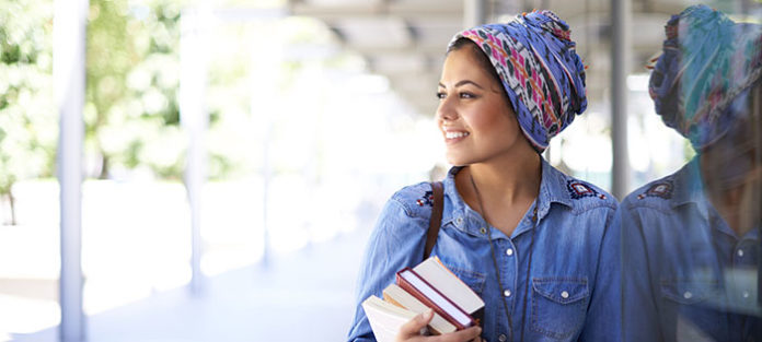 Young woman smiling while walking and carrying her books