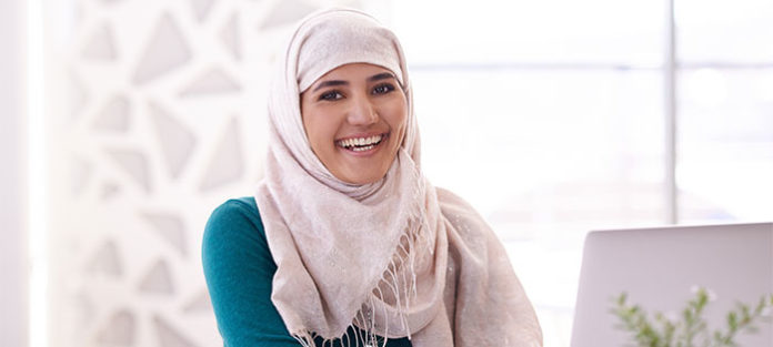 Young woman smiling while working on her laptop