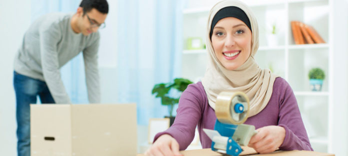 Female wearing hijab packing boxes with a friend