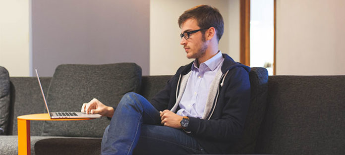 man-relax-couch-study_cropped Young man using his laptop while sitting on the couch in the student lounge