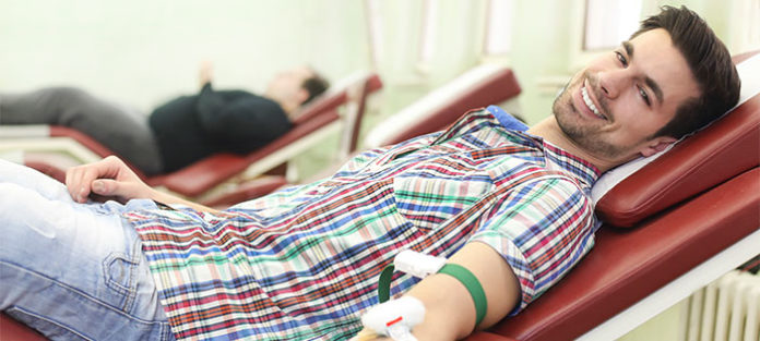 Male college student giving blood Male college student giving blood