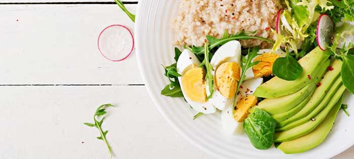 Healthy breakfast plate of eggs, avocado, and oatmeal