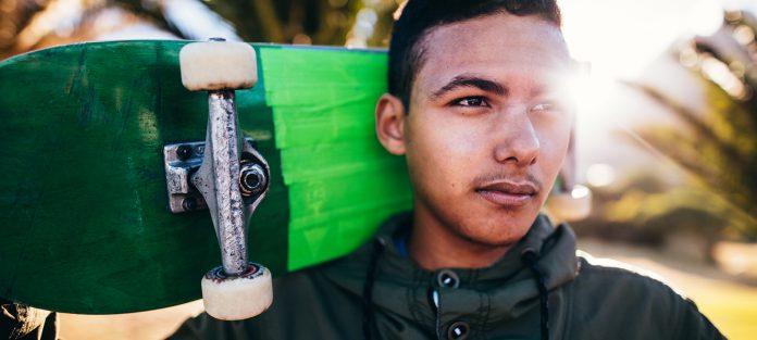 Pensive boy holding skateboard