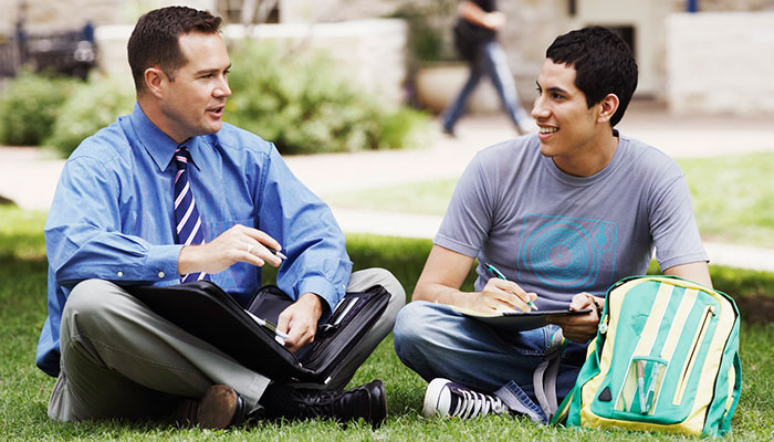 Student talking with teacher on the grass