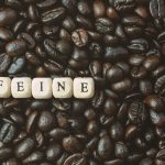 Coffee beans fill background with letter tiles spelling caffeine, symbolizing energy, alertness, and stimulation effects.