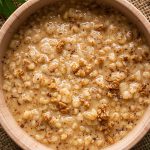 UCookbook: Savory oatmeal with garlicky greens Bowl of savory oatmeal topped with grains and spices on rustic table