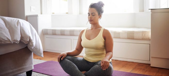 young woman meditating in bedroom