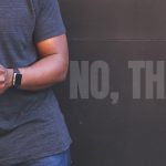 Man texting on his phone, with large faded words reading “NO, THANKS!” behind him.