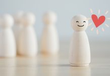 Thriving in your own space: 10 reasons introverts have it right Smiling wooden figure standing apart from group, symbolizing introversion and self-contentment