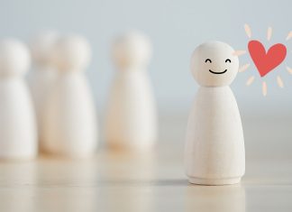 Thriving in your own space: 10 reasons introverts have it right Smiling wooden figure standing apart from group, symbolizing introversion and self-contentment