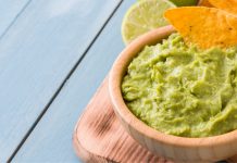 Party-ready green pea guacamole, no avocados required green pea guacamole on serving platter with tortilla chips and lime | guacamole recipe