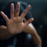 Ask the counselor: “How do you deal with negative feelings from a traumatic event in your past?” Person raising hand defensively, symbolizing trauma, boundaries, or emotional protection.