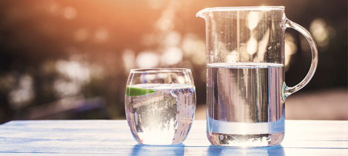 drinking glass and pitcher of water on picnic table