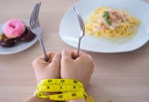 Beyond the myths: What everyone should know about eating disorders Hands holding fork and spoon with measuring tape, symbolizing eating disorder struggles