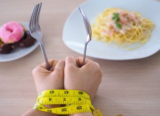 Beyond the myths: What everyone should know about eating disorders Hands holding fork and spoon with measuring tape, symbolizing eating disorder struggles