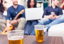 How binge drinking hurts your brain—and your grades Plastic cups of beer on table with college students socializing in background, representing binge drinking culture.