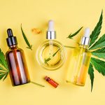 What Science really says about CBD's benefits Bottles of CBD oil with droppers and capsules surrounded by cannabis leaves on yellow background.