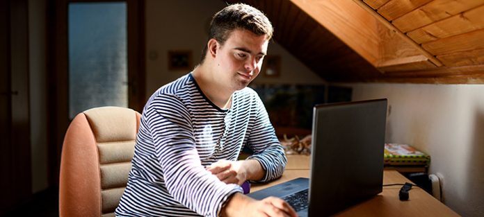 Young man with down syndrome using laptop indoors | tips to stay motivated in college