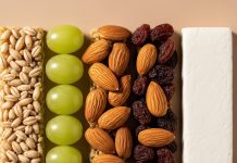 Snack smart: The real deal on 4 popular protein picks (and what to try instead) Neatly arranged snack ingredients including grains, grapes, almonds, raisins, and protein bar on neutral background.