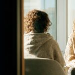 Two people sit facing each other in conversation, suggesting attentive listening, empathy, and meaningful communication.