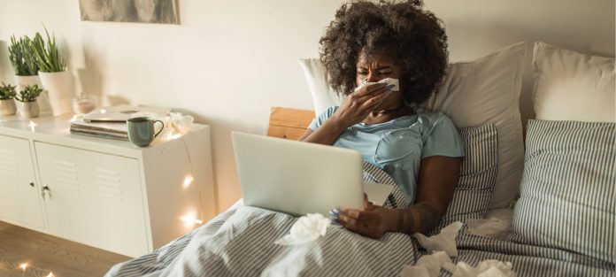 sick girl in bed looking at computer