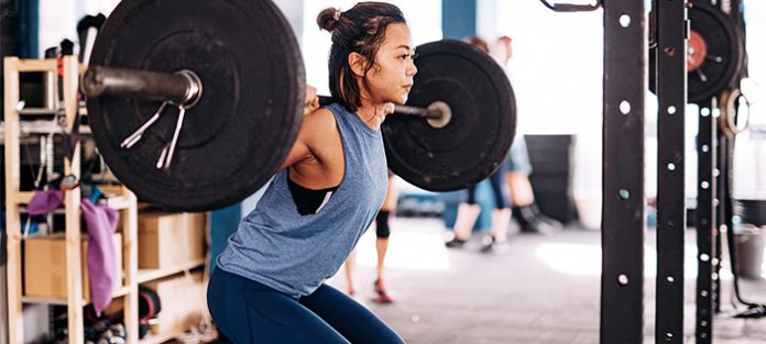 asian female squatting with barbell