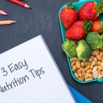 3 Easy Nutrition Tips to Help You Thrive at School A lunchbox with strawberries, broccoli, nuts, and a notebook saying “3 Easy Nutrition Tips.”