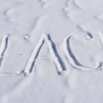 The word “PEACE” written clearly in fresh snow on a bright winter day.