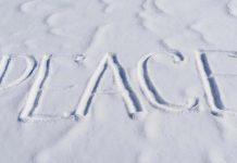 The word “PEACE” written clearly in fresh snow on a bright winter day.