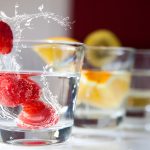 7 smart strategies for navigating the college drinking scene Raspberries splash into a glass of water; citrus-infused drinks sit in the background.