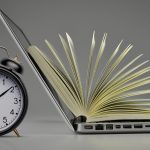 Alarm clock, laptop, and open book showing balance between time management and online learning.