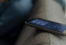A smartphone with a dark screen lies on a couch, displaying the time and notifications.