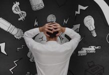 A man holding his head in frustration, surrounded by blackboard-style doodles of stress-related symbols like dollar signs, light bulbs, and arrows.