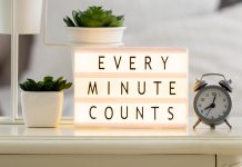 A clock and lightbox with "Every Minute Counts" message on a bedside table.