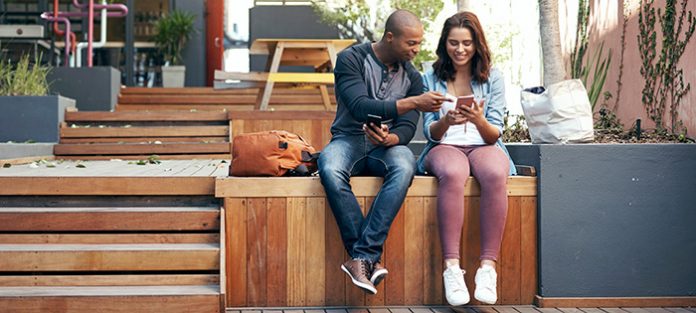 guy and girl sitting outside sharing phones