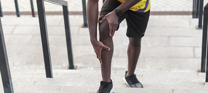 guy running up stairs holding knee